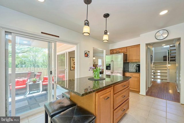 kitchen featuring backsplash, light tile patterned floors, decorative light fixtures, and stainless steel fridge with ice dispenser