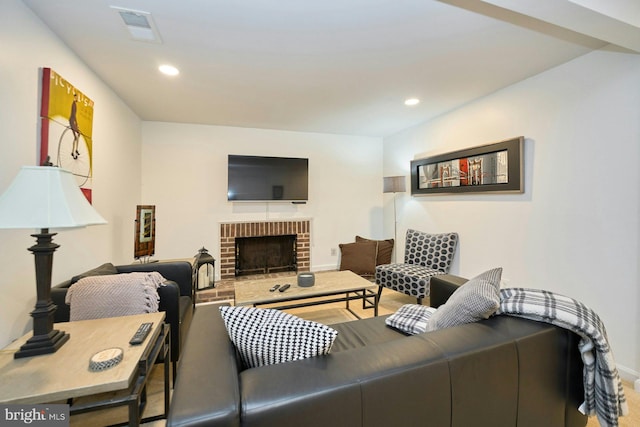 living room with a brick fireplace, recessed lighting, baseboards, and visible vents