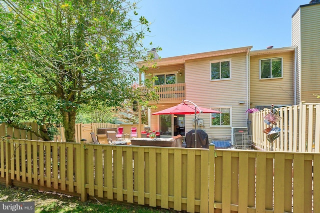 back of house featuring a fenced backyard, a chimney, and a balcony