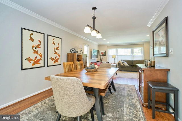 dining space with baseboards, ornamental molding, and wood finished floors