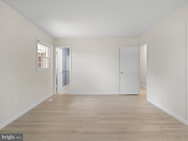 spare room featuring baseboards, light wood-style flooring, and visible vents