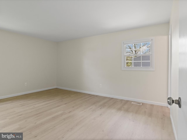 unfurnished room with baseboards, light wood-type flooring, and visible vents