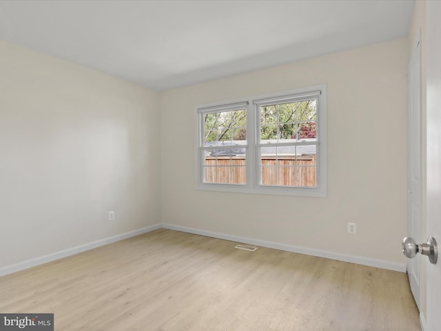 unfurnished room featuring baseboards, wood finished floors, and visible vents