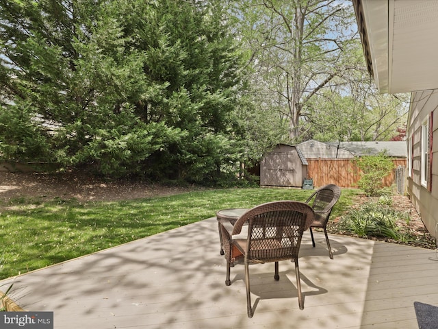 view of patio / terrace with a wooden deck, fence, an outbuilding, and a storage unit