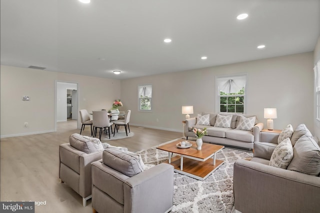 living area featuring baseboards, light wood finished floors, and a wealth of natural light