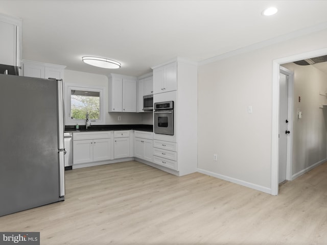 kitchen with white cabinets, stainless steel appliances, a sink, and light wood-style flooring
