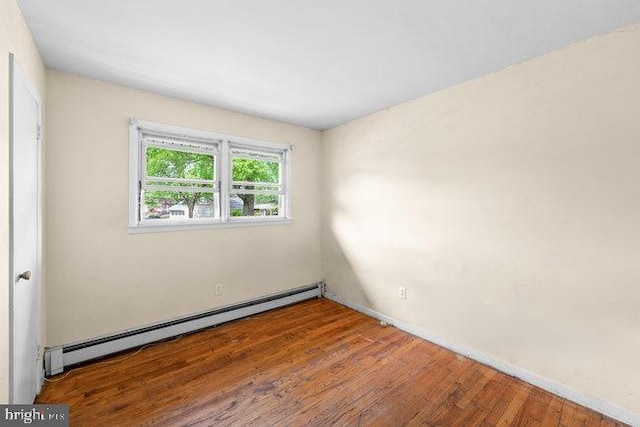 unfurnished room featuring a baseboard radiator and wood finished floors