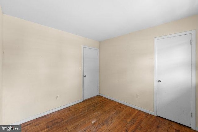 spare room featuring baseboards and wood finished floors