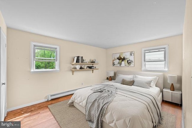 bedroom with wood finished floors, radiator, baseboards, and multiple windows