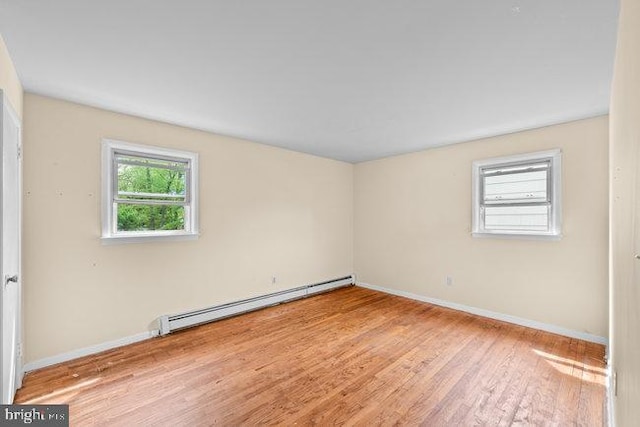 unfurnished room with baseboards, wood finished floors, and baseboard heating