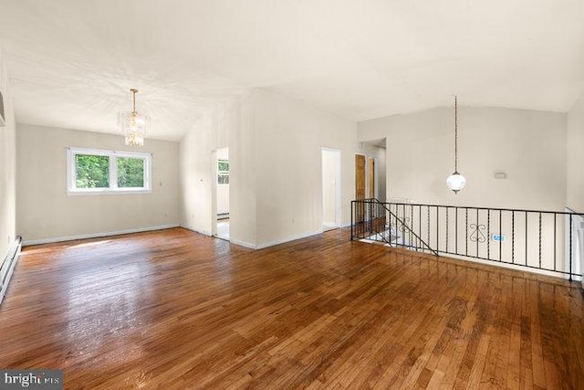 spare room with an inviting chandelier, baseboards, lofted ceiling, and hardwood / wood-style floors