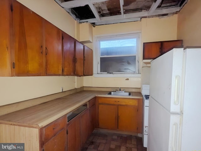 kitchen featuring a sink, light countertops, brown cabinetry, and white appliances