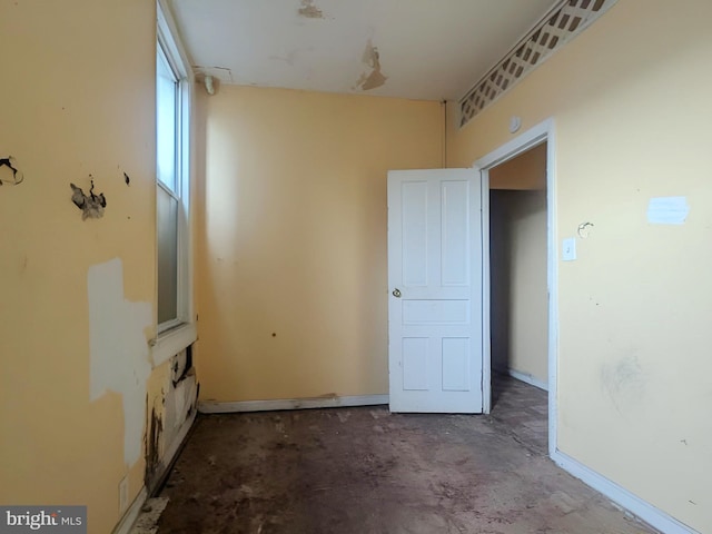 empty room with baseboards and concrete flooring