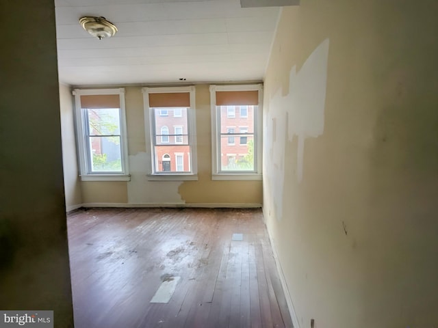 unfurnished room featuring a healthy amount of sunlight, baseboards, and hardwood / wood-style floors