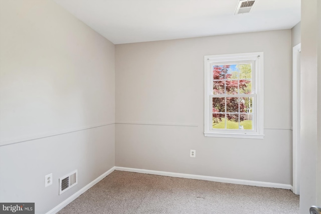 carpeted spare room with baseboards, visible vents, and plenty of natural light