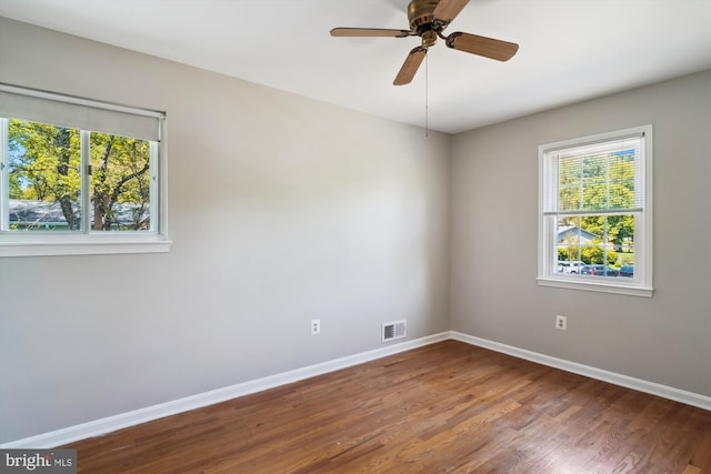 spare room with baseboards, visible vents, a wealth of natural light, and wood finished floors