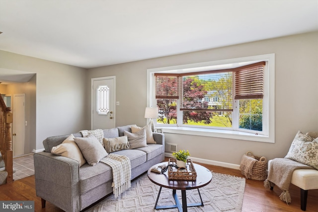 living room featuring visible vents, baseboards, and wood finished floors
