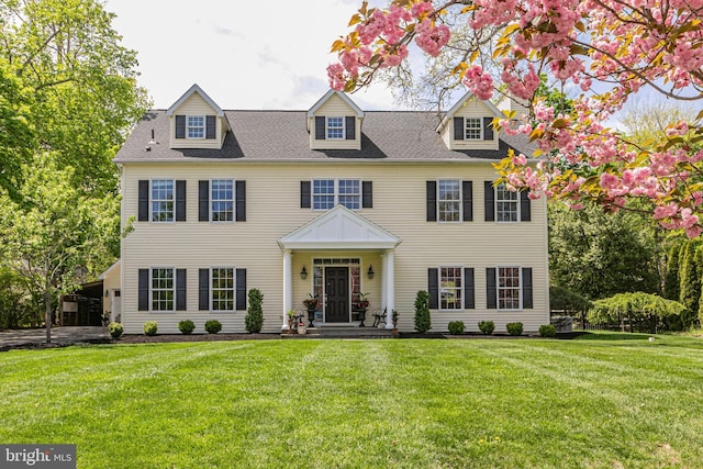 view of front facade featuring a shingled roof and a front lawn
