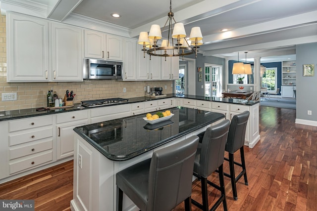 kitchen featuring beamed ceiling, a peninsula, dark wood-style floors, a chandelier, and stainless steel appliances