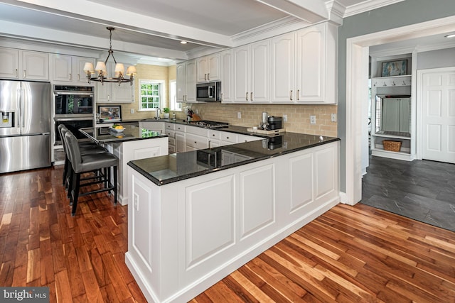 kitchen with crown molding, backsplash, appliances with stainless steel finishes, and an inviting chandelier