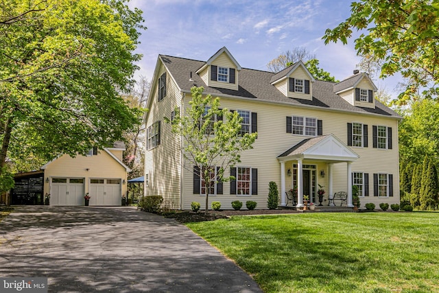 colonial house with an outdoor structure, a garage, and a front lawn