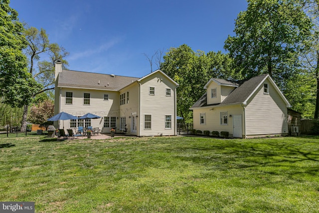 rear view of house featuring a lawn, a patio, and fence