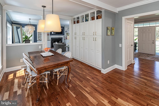 dining space with baseboards, dark wood finished floors, crown molding, and a fireplace