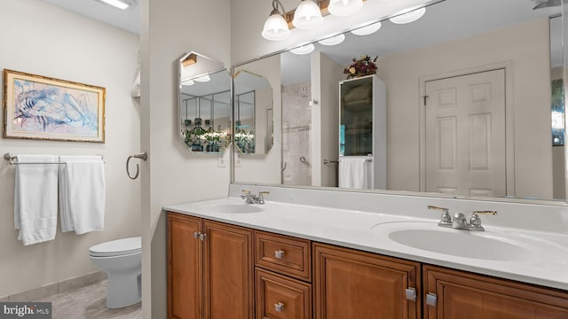 bathroom featuring a sink, double vanity, toilet, and baseboards