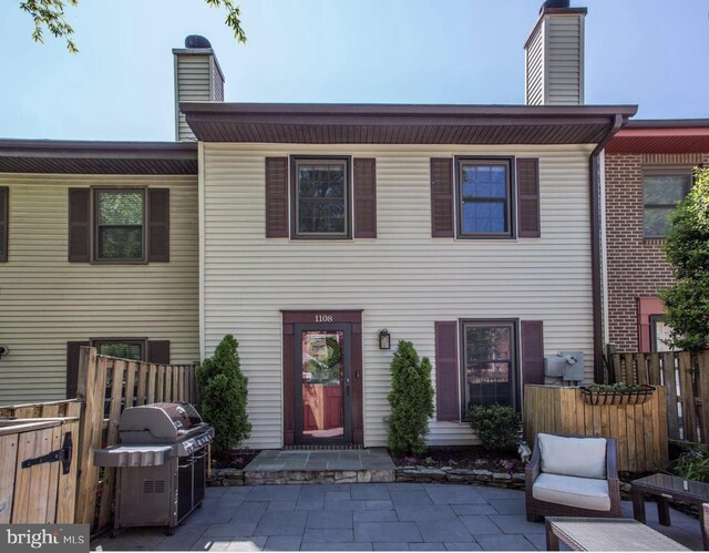 view of front of property featuring fence, a chimney, and a patio area