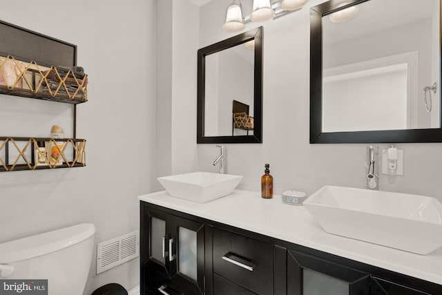 102 N Glover St, Baltimore, MD 21224 - bathroom featuring double vanity, toilet, visible vents, and a sink