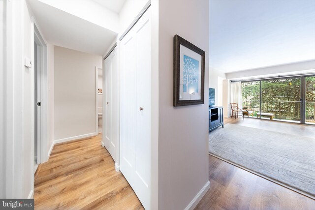 hall featuring light wood finished floors and baseboards