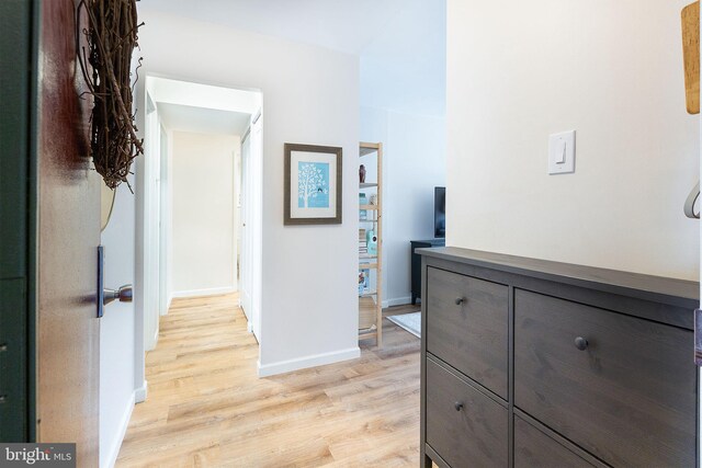 corridor featuring light wood finished floors and baseboards