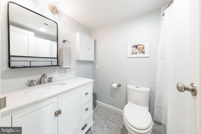 bathroom featuring toilet, vanity, and baseboards