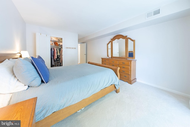 carpeted bedroom with a walk in closet, a closet, and baseboards