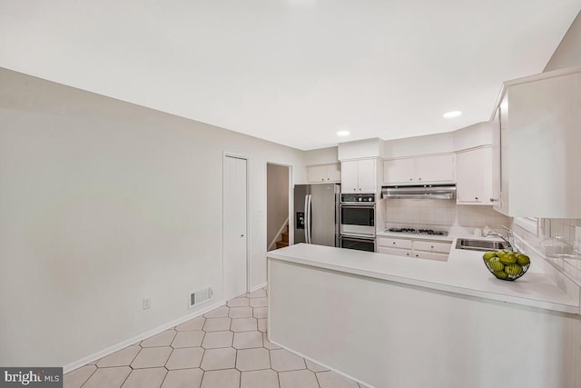 205 Dunbeath Ct, Lutherville Timonium, MD 21093 - kitchen featuring appliances with stainless steel finishes, under cabinet range hood, a sink, light countertops, and decorative backsplash