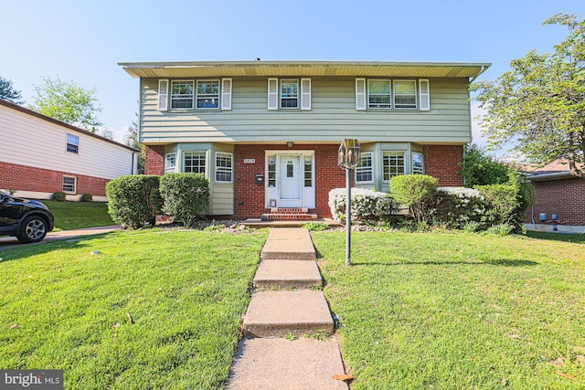 colonial home with brick siding and a front yard