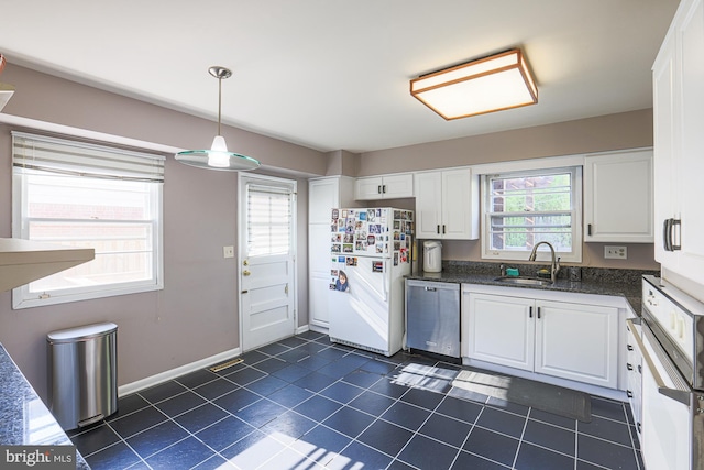 kitchen with hanging light fixtures, a sink, white appliances, white cabinetry, and dark tile patterned flooring