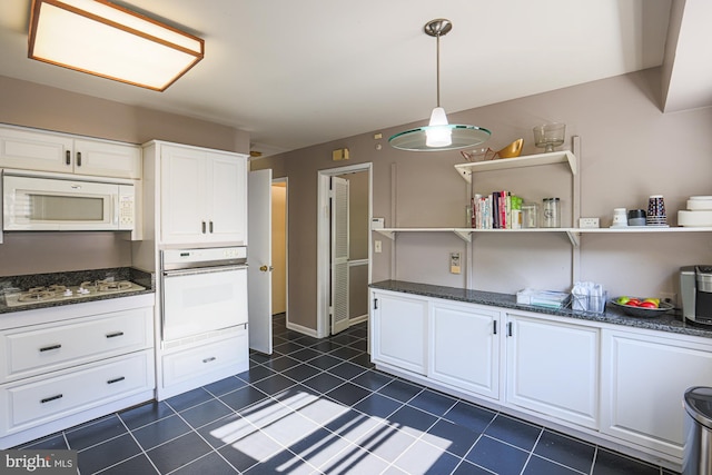 kitchen with open shelves, dark tile patterned flooring, dark stone countertops, white appliances, and white cabinetry