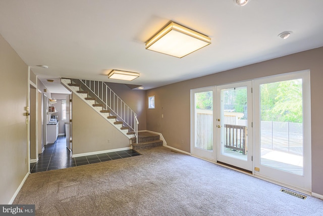 entryway with dark colored carpet, stairs, baseboards, and visible vents