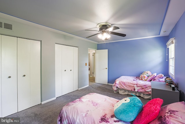 bedroom with ceiling fan, visible vents, baseboards, multiple closets, and carpet