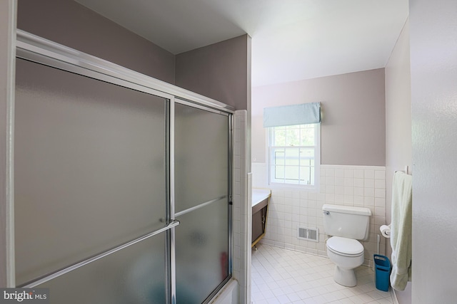 bathroom with tile patterned flooring, a wainscoted wall, tile walls, an enclosed shower, and visible vents