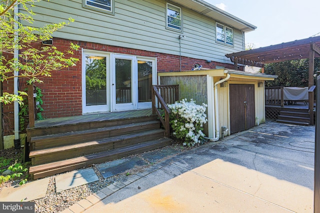 back of property featuring a wooden deck, a pergola, and brick siding
