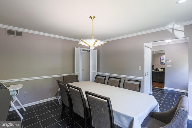 dining room featuring dark tile patterned floors, baseboards, crown molding, and visible vents