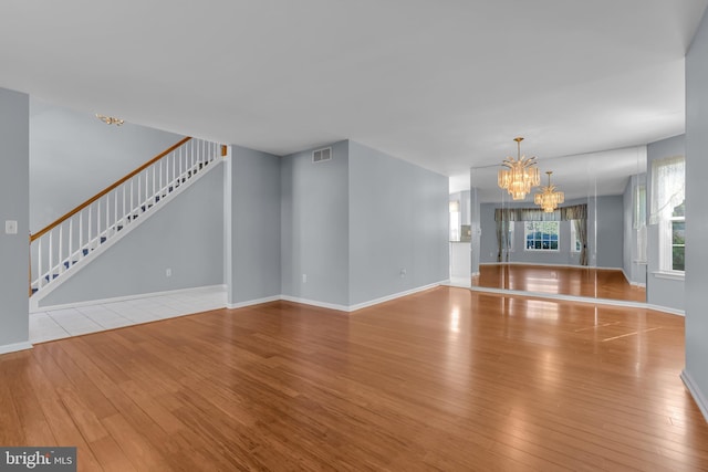 12 Jon Dr, Barnegat, NJ 08005 - unfurnished living room with baseboards, wood-type flooring, visible vents, a chandelier, and stairway