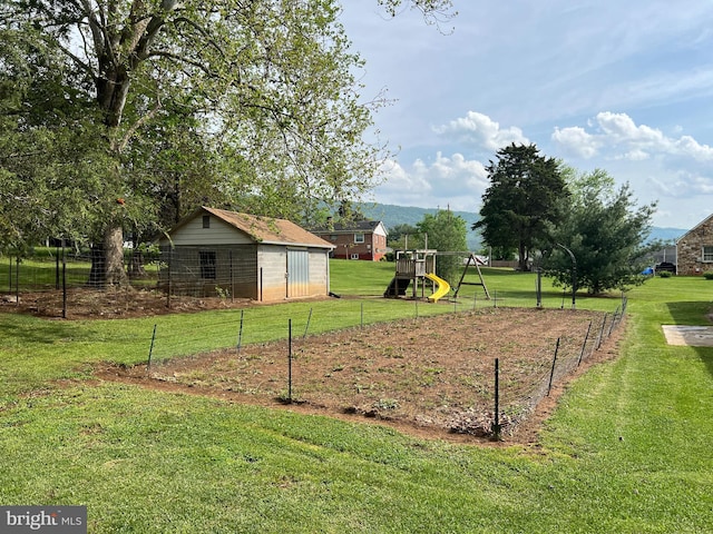 exterior space with a playground, fence, and an outbuilding
