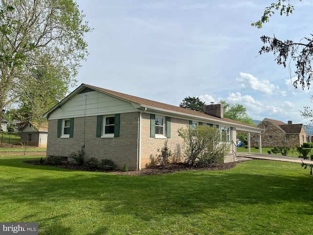 view of side of home featuring a lawn, a chimney, and a carport