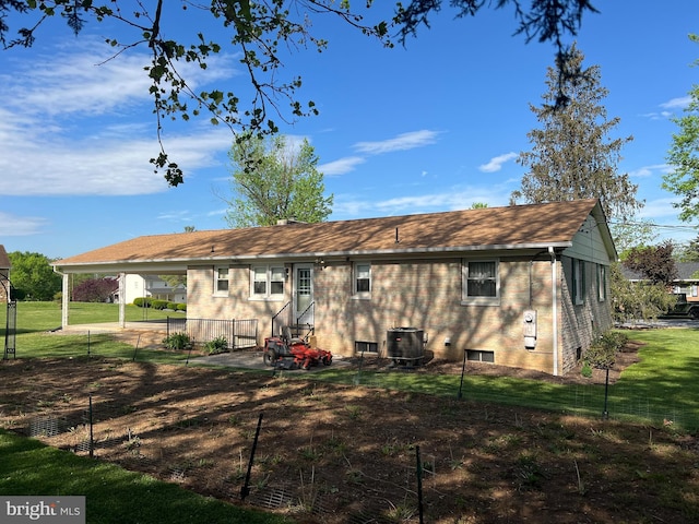 back of property with fence, central AC unit, a yard, and brick siding