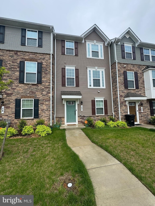 multi unit property with stone siding and a front lawn