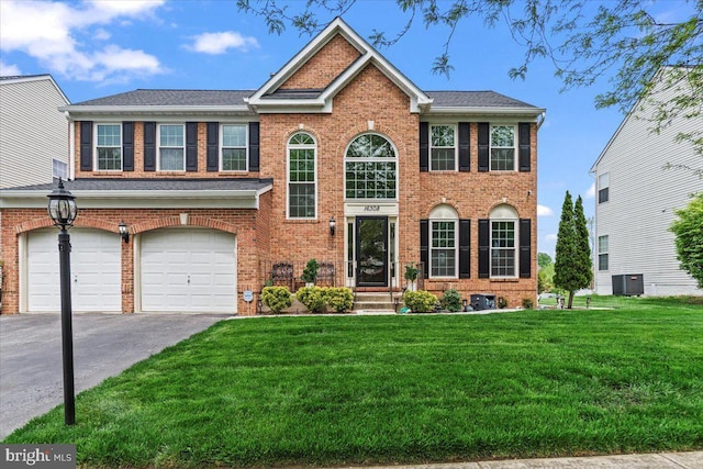 view of front of house with an attached garage, a front lawn, brick siding, aphalt driveway, and cooling unit