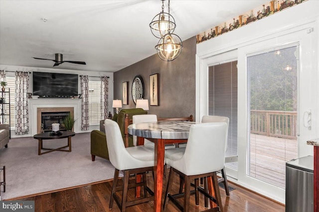 dining space featuring a glass covered fireplace, ceiling fan, and dark wood-type flooring
